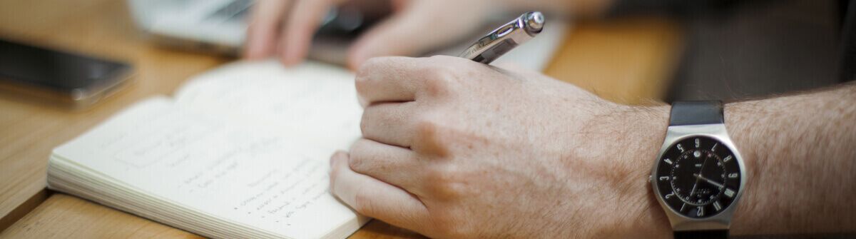 Asesoría Loyola Asesoría Loyola. Imagen decorativa de una mano escribiendo en un cuaderno